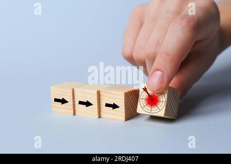 Femme mettant cube avec icône de cible dans la rangée de cubes avec des flèches sur fond clair, gros plan Banque D'Images