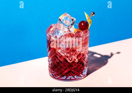 Cocktail alcoolisé Sbagliato Rosa avec liqueur rouge italienne et apéritif, rose champagne ou vin mousseux, décoré de zeste, brick bleu été Banque D'Images