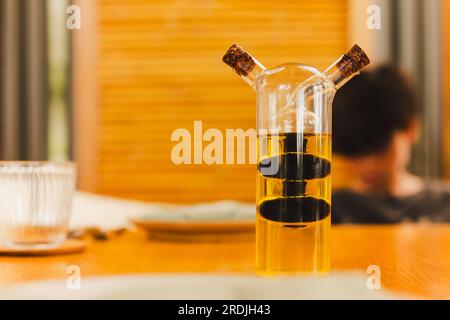 Une bouteille en verre avec de l'huile d'olive et du vinaigre balsamique sur la table. Banque D'Images