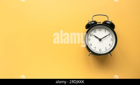 Concept de temps, rappel, compte à rebours, alerte, date limite. Réveil isolé sur fond jaune.Copier l'espace. Banque D'Images