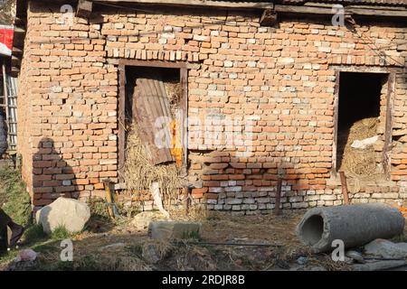 Bâtiments de village composés de briques, bâtiments utilisés comme granges pour le stockage de vieilles choses inutilisées, fond de texture de mur de briques, ruiné vieille brique h Banque D'Images