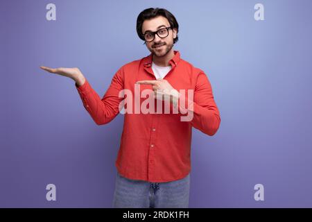 bel homme millénaire brunette de 35 ans avec des cheveux magnifiques montre sa main sur le côté Banque D'Images