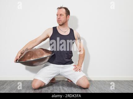 Homme assis sur le sol jouant handpan Banque D'Images