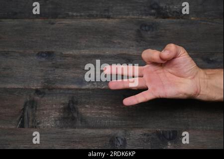 Main d'homme montrant des doigts sur fond en bois comptant le numéro 3 montrant trois doigts. Banque D'Images