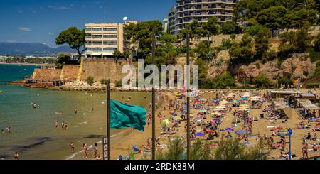 Plage de Capellans, à Salou, pleine de baigneurs avec le drapeau vert au premier plan (Tarragone, Catalogne, Espagne) ESP : la playa de los Capellans, Salou Banque D'Images