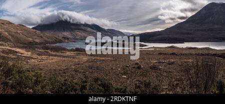 Panorama à l'est du Loch Lurgainn avec cul Beag sommet dans les nuages, landes rugueuses et gorse au premier plan le tout sous un soleil bruyant avec des nuages minces Banque D'Images