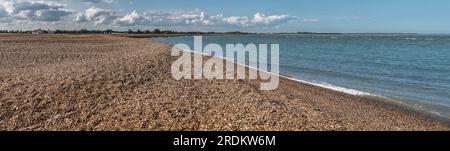 Large Panaorama vue sur la plage et la mer à Shingle Street dans le Suffolk regardant Orford Haven et Orford Ness au loin sous le ciel bleu et les nuages Banque D'Images