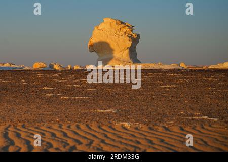 Soleil vu se coucher dans le désert blanc, Egypte. De l'érosion des volcans et d'une montagne de quartz, aux roches altérées et aux formations rocheuses de craie blanche, Black and White Desert fait partie de la dépression de Frarafra dans le désert du Sahara et se situe dans la partie occidentale de l'Égypte. Le vaste désert est relié aux routes principales qui sont proches de la frontière libyo-égyptienne où il est maintenant lourdement armé avec une présence militaire. Le paysage naturel bizarre qui s'élève d'un fond océanique il y a des millions d'années est maintenant laissé avec des formations karstiques calcaires qui ressemblent à la surface d'autres planètes de l'univers. (Photo de Banque D'Images