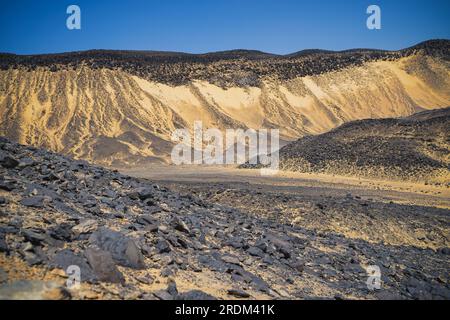 13 avril 2023, QSAR El Farafra, Egypte : une vue panoramique du désert noir en Egypte où les chaînes de montagnes sont recouvertes de petites pierres noires altérées par des volcans il y a plusieurs millions d'années. De l'érosion des volcans et d'une montagne de quartz, aux roches altérées et aux formations rocheuses de craie blanche, Black and White Desert fait partie de la dépression de Frarafra dans le désert du Sahara et se situe dans la partie occidentale de l'Égypte. Le vaste désert est relié aux routes principales qui sont proches de la frontière libyo-égyptienne où il est maintenant lourdement armé avec une présence militaire. Le paysage naturel bizarre s'élevant d'un Banque D'Images