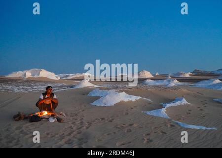 13 avril 2023, QSAR El Farafra, Egypte : un guide vu commençant un feu de camp dans le désert blanc, Egypte. De l'érosion des volcans et d'une montagne de quartz, aux roches altérées et aux formations rocheuses de craie blanche, Black and White Desert fait partie de la dépression de Frarafra dans le désert du Sahara et se situe dans la partie occidentale de l'Égypte. Le vaste désert est relié aux routes principales qui sont proches de la frontière libyo-égyptienne où il est maintenant lourdement armé avec une présence militaire. Le paysage naturel bizarre qui s'élève d'un fond océanique il y a des millions d'années est maintenant laissé avec des formations karstiques calcaires qui ressemblent au s. Banque D'Images