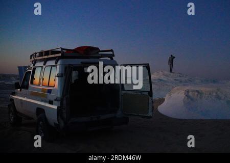 13 avril 2023, QSAR El Farafra, Egypte : un homme vu debout sur un rocher calcifié dans le désert blanc, Egypte. De l'érosion des volcans et d'une montagne de quartz, aux roches altérées et aux formations rocheuses de craie blanche, Black and White Desert fait partie de la dépression de Frarafra dans le désert du Sahara et se situe dans la partie occidentale de l'Égypte. Le vaste désert est relié aux routes principales qui sont proches de la frontière libyo-égyptienne où il est maintenant lourdement armé avec une présence militaire. Le paysage naturel bizarre qui s'élève d'un fond océanique il y a des millions d'années est maintenant laissé avec des formations karstiques calcaires qui ressemblent à t Banque D'Images