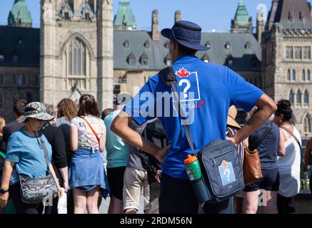 Ottawa, Ontario, Canada. 19 juillet 2023. 19 juillet 2023. Un guide répond aux questions pendant la cérémonie de la relève de la garde, les guides font partie des visites gratuites de la Colline du Parlement. Il s'agit d'une performance musicale de la bande de la garde de cérémonie sur la Colline du Parlement à Ottawa, Ontario, Canada. Le changement a lieu à 10:00 h tous les jours entre le 28 juin et le 25 août. (Image de crédit : © Ralph Lauer/ZUMA Press Wire) USAGE ÉDITORIAL SEULEMENT! Non destiné à UN USAGE commercial ! Banque D'Images