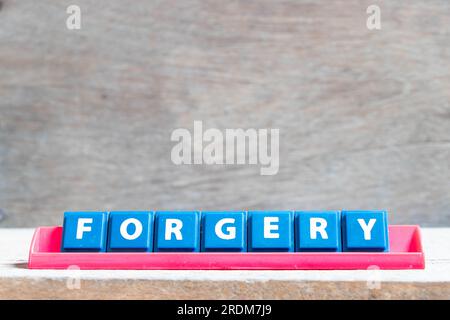 Lettre de l'alphabet de tuile avec le mot falsification dans le rack de couleur rouge sur fond de bois Banque D'Images