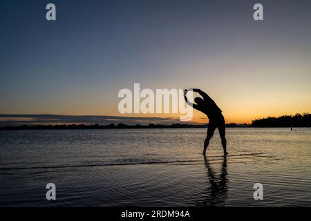 La pratique du yoga posture de l'arbre palm - sunrise silhouette d'un homme sur une plage du lac, Boyd Lake State Park dans le nord du Colorado Banque D'Images