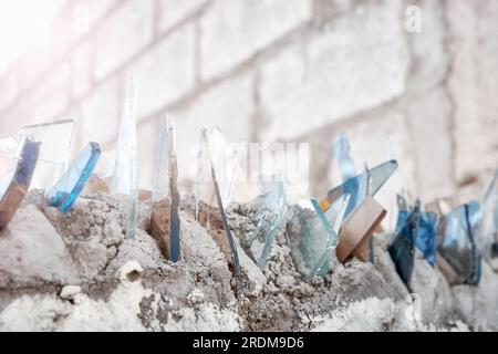 Gros plan image de fragments de verre sur un mur, utilisé pour sécuriser la propriété privée, mise au point sélective. Banque D'Images