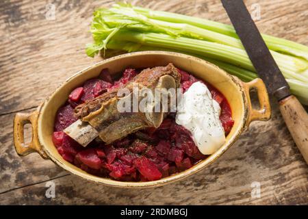 Soupe Borscht maison servie avec une côte de bœuf cuite lentement et une cuillerée de crème fraîche. Affiché sur une planche à découper en bois. Angleterre Royaume-Uni GB Banque D'Images