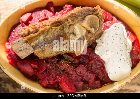 Soupe Borscht maison servie avec une côte de bœuf cuite lentement et une cuillerée de crème fraîche. Affiché sur une planche à découper en bois. Angleterre Royaume-Uni GB Banque D'Images