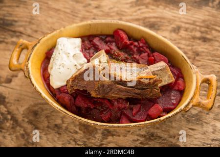 Soupe Borscht maison servie avec une côte de bœuf cuite lentement et une cuillerée de crème fraîche. Affiché sur une planche à découper en bois. Angleterre Royaume-Uni GB Banque D'Images