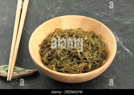 Nouille Shirataki verte épicée ou Kkonjac en fond de bol en bois. Cuisine japonaise Banque D'Images