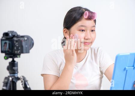 mignon blogger asiatique fille applique la crème sur les joues. En face de la caméra pour enregistrer vlog vidéo en direct streaming à la maison.Business en ligne inf Banque D'Images