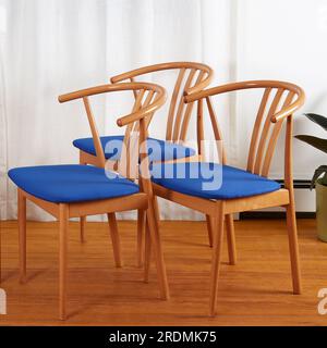 Trois chaises en bois minimalistes modernes du milieu du siècle avec sièges bleus. chaises de style wishbone des années 1960. Banque D'Images