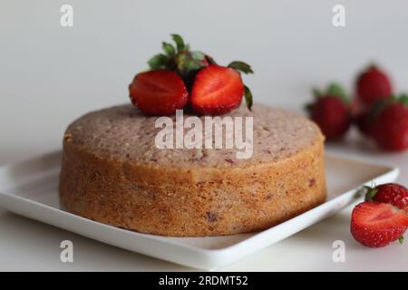 Gâteau aux fraises. Un simple gâteau à l'heure du thé, aromatisé avec de la purée de fraises fraîche. Servi avec fraises fraîches coupées et sauce fraise. Tourné sur blanc Banque D'Images