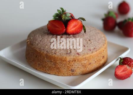 Gâteau aux fraises. Un simple gâteau à l'heure du thé, aromatisé avec de la purée de fraises fraîche. Servi avec fraises fraîches coupées et sauce fraise. Tourné sur blanc Banque D'Images