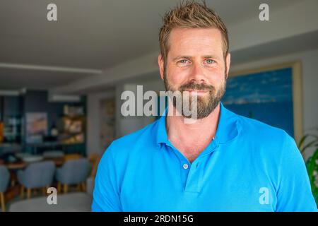 Gros plan portrait de souriant homme caucasien des années 30 regarder la caméra posant dans son propre appartement ou appartement. Banque D'Images