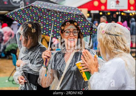Henham Park, Suffolk, Royaume-Uni. 22 juillet 2023. Une fête de poule met un visage courageux sur elle - le temps change à la pluie prolongée et les gens réagissent de manière différente - certains portent des ponchos jetables, certains continuent et se mouillent, la plupart sont encore de bonne humeur - le Latitude Festival 2023, Henham Park. Crédit : Guy Bell/Alamy Live News Banque D'Images