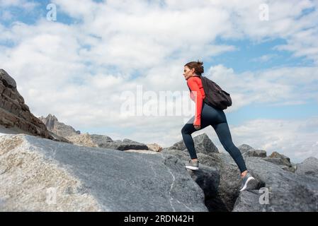 Femme aventureuse marchant jusqu'à une montagne rocheuse. Banque D'Images