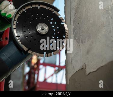 Master coupe un mur en béton avec une scie circulaire diamantée. Banque D'Images