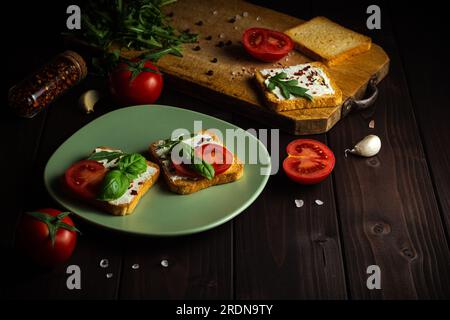 Cuisson des sandwichs avec des légumes pour le petit déjeuner ensemble à la table en bois. Fond en bois Banque D'Images