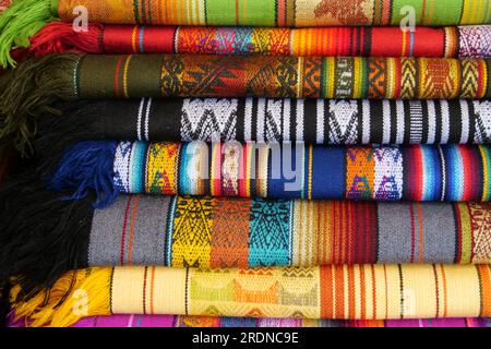 Tissu traditionnel plié aux couleurs vives à vendre au marché Otavalo en Équateur Banque D'Images