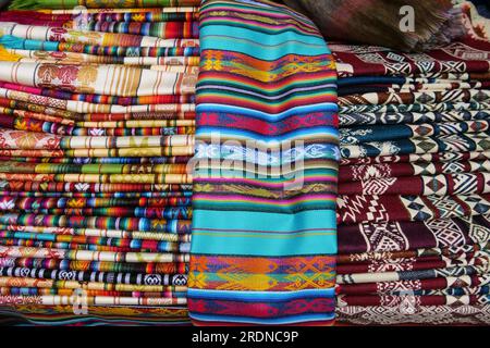 Tissu traditionnel plié aux couleurs vives à vendre au marché Otavalo en Équateur Banque D'Images