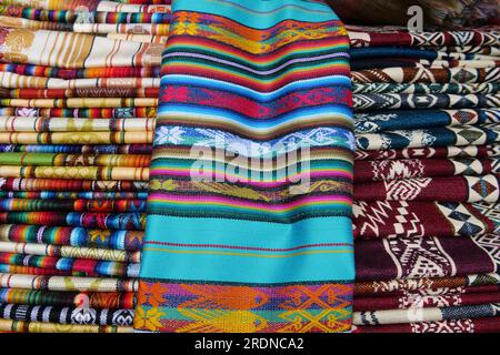 Tissu traditionnel plié aux couleurs vives à vendre au marché Otavalo en Équateur Banque D'Images