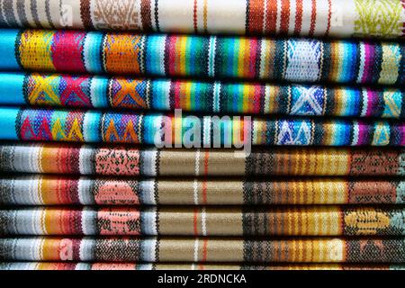 Gros plan de tissu traditionnel plié aux couleurs vives à vendre au marché Otavalo en Équateur Banque D'Images