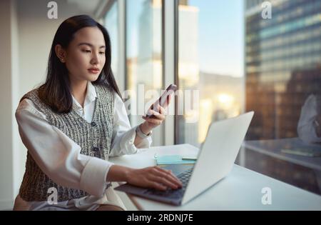 Jeune femme d'affaires asiatique travaillant en utilisant le téléphone et l'ordinateur portable dans le bureau. Banque D'Images