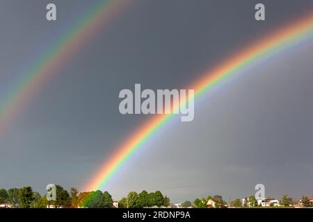 Un bel arc-en-ciel double coloré sur fond d'un ciel dangereux et orageux Banque D'Images