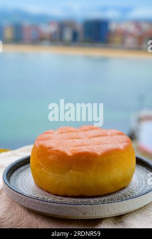 Fromage de vache fumé espagnol de Pria, Asturies, servi en plein air avec vue sur la plage de San Lorenzo et la promenade de Gijon Banque D'Images