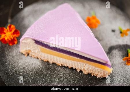 Une tranche de Gourmet Ube Entremet Cake également connu sous le nom d'igname pourpre avec gâteau éponge en couches, gelée ube, gelée de lait évaporée et mousse ube, recouverte d'un Banque D'Images