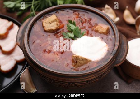 Savoureux borscht avec de la crème sure dans un bol servi sur la table brune, closeup Banque D'Images