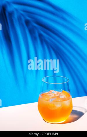 Cocktail alcoolisé Bee's Knees avec gin sec, jus de citron et sirop de miel, fond bleu d'été lumineux, lumière dure et ombres Banque D'Images