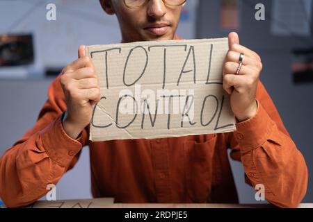 Conspiration et un homme s'assied et tient une inscription - contrôle total dans ses mains. Théoricien du complot et fausses nouvelles. Politique et théorie du complot. Banque D'Images