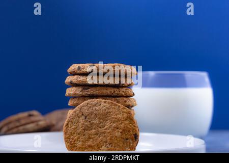 Biscuits en pile avec verre de lait frais sur fond bleu (marque américaine célèbre de biscuits) Banque D'Images