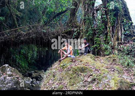 Des hommes locaux assis sur un gros rocher près du double pont de racine vivante, près du village de Padu à Meghalaya, en Inde Banque D'Images