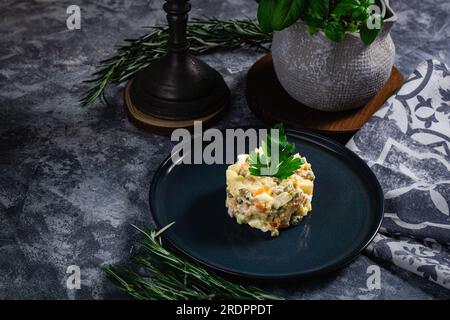 Salade au persil, Olivier, dans un bol noir sur la table, mise au point sélective. Salade russe traditionnelle avec espace copie. Banque D'Images