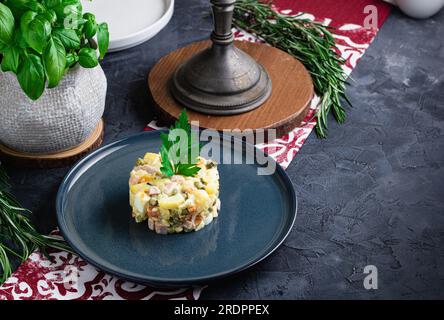 Salade au persil, Olivier, dans un bol noir sur la table, mise au point sélective. Salade russe traditionnelle avec espace copie. Banque D'Images