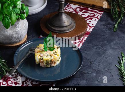 Salade au persil, Olivier, dans un bol noir sur la table, mise au point sélective. Salade russe traditionnelle avec espace copie. Banque D'Images