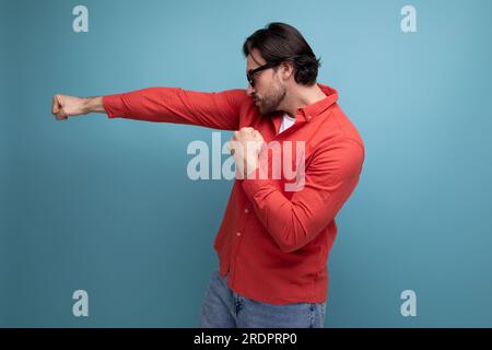 bel homme millénaire brunette de 35 ans avec des cheveux magnifiques montre sa force Banque D'Images