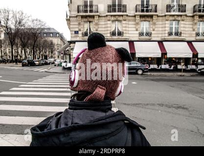 PHOTOGRAPHIE DE RUE PARIS - JEUNE FILLE AVEC UN BONNET D'HIVER ET CASQUE DE MUSIQUE DANS LA RUE - SAISON D'HIVER © F.BEAUMONT Banque D'Images
